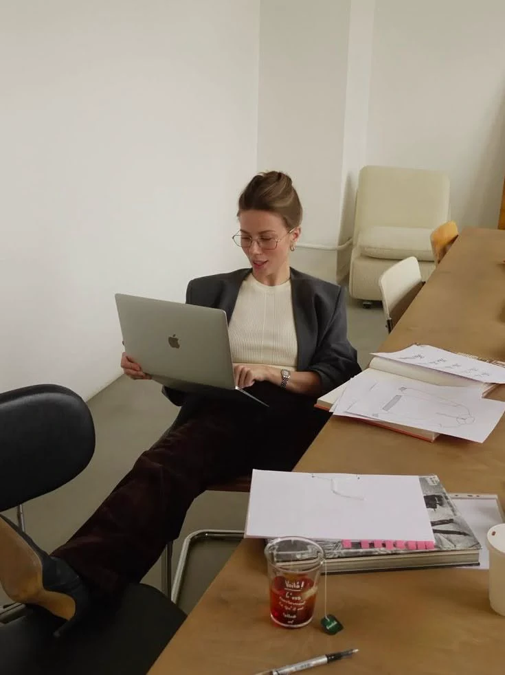 A designer works through handwritten notes beside a closed MacBook